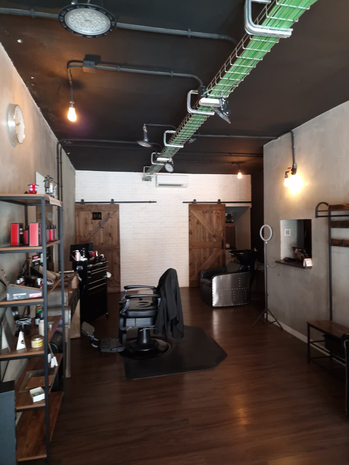 Interior de la barbería Sonrisa Canalla: sillón de barbero, lavacabezas y estanterías de producto en un local de estilo industrial